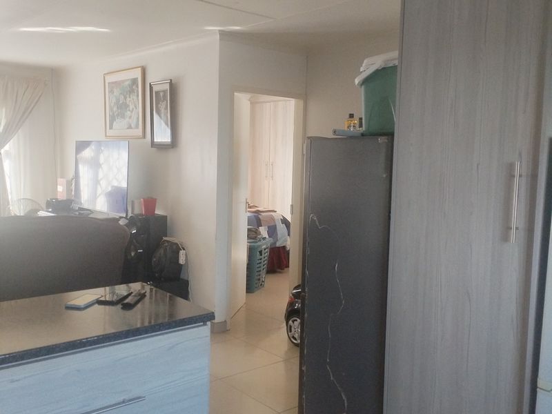 Open plan living area featuring tiled flooring and built-in cabinetry, with a view through to an adjacent bedroom.