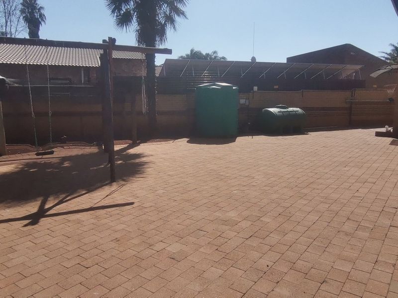 A spacious rear paved courtyard featuring a water storage tank and boundary wall, providing a functional outdoor area.