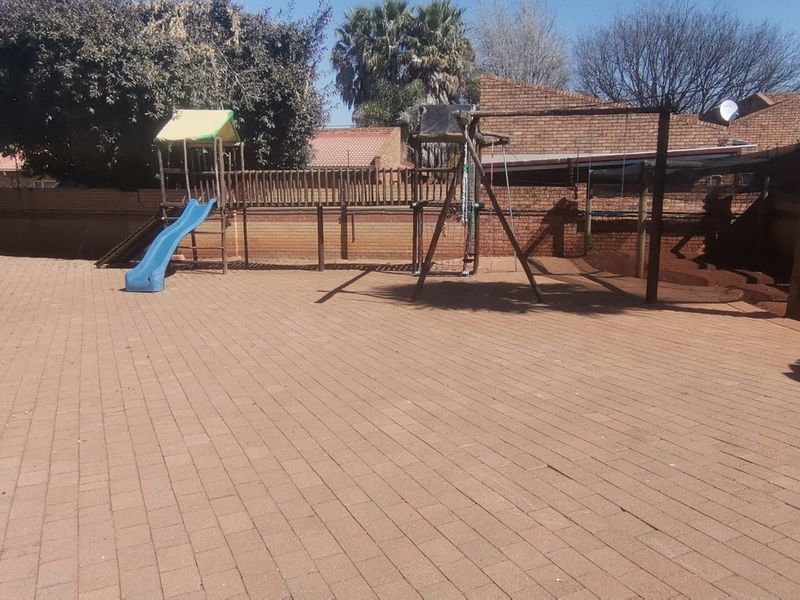 A spacious rear courtyard featuring extensive brick paving and a secure perimeter brick wall, providing a functional outdoor area.