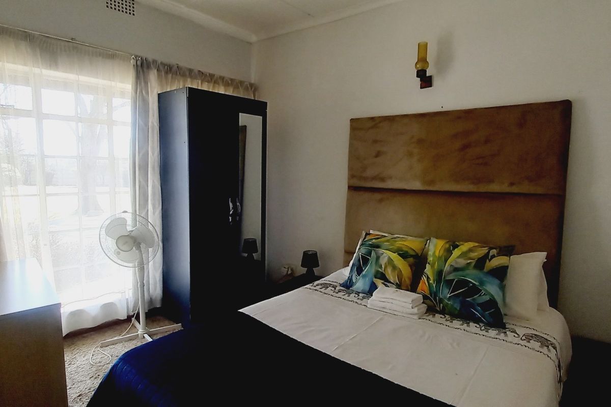 A functional bedroom featuring a large window for natural light and a wall-mounted light fixture.