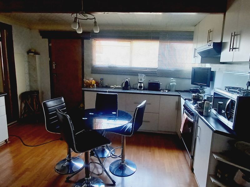 A functional kitchen featuring built-in cabinetry, laminate countertops, and integrated appliances, with a dedicated dining area and wood-look flooring.
