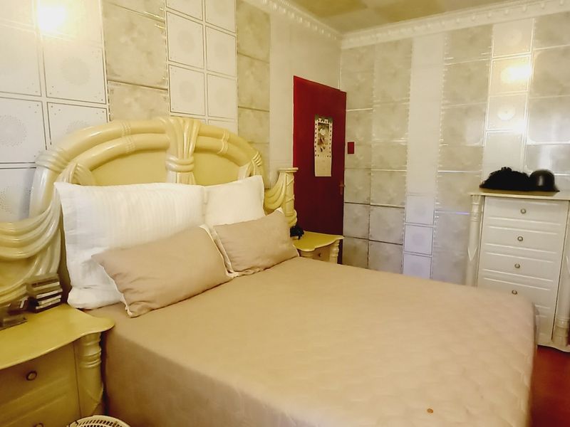 A bedroom featuring built-in wardrobes, decorative wall tiling, and crown molding. The space would benefit from modern updates to finishes.