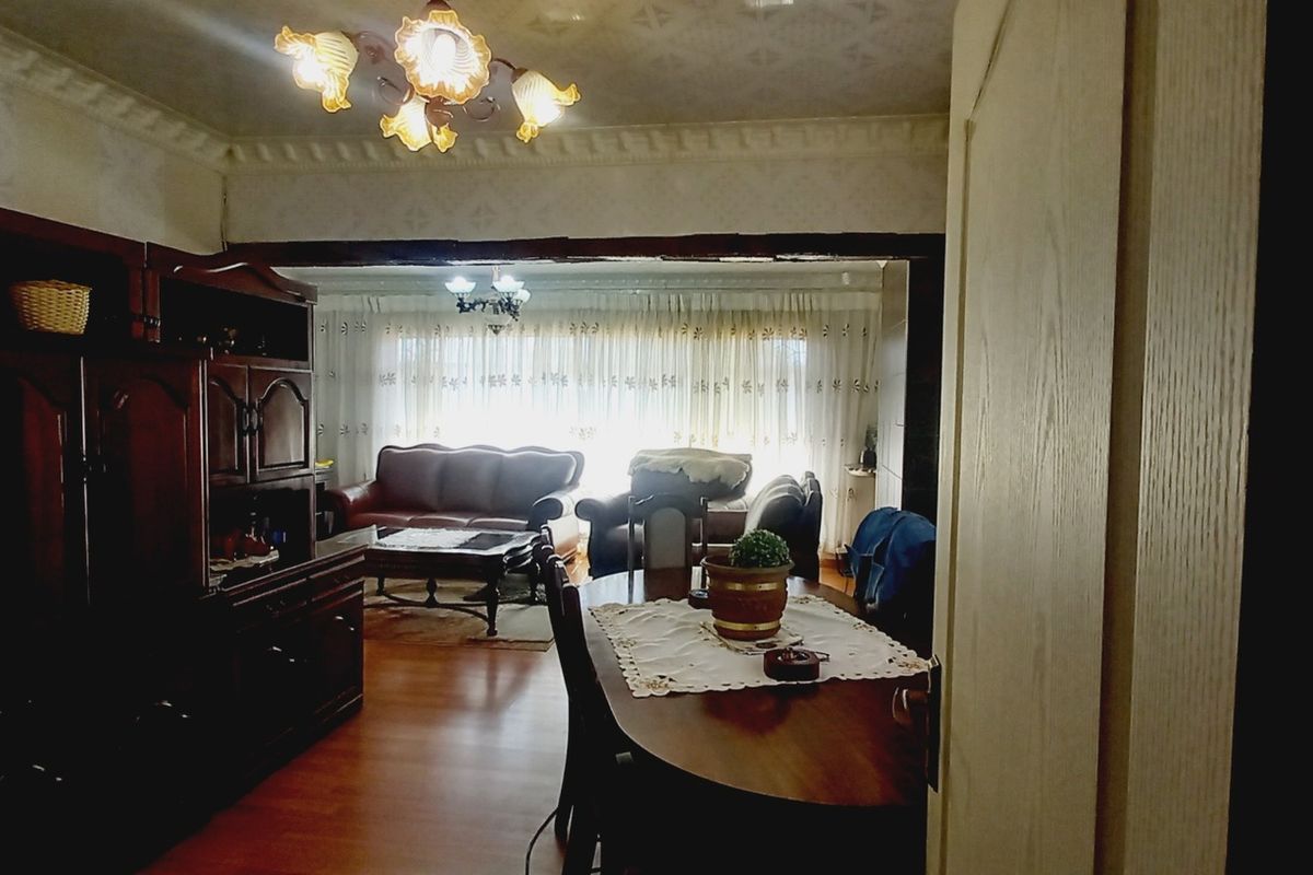 Open plan living and dining area featuring laminate flooring and decorative ceiling cornices, currently requiring cosmetic updates to the wall finishes.