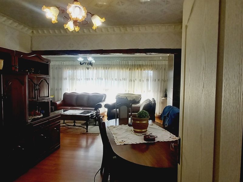 Open plan living and dining area featuring laminate flooring and decorative ceiling cornices, currently requiring cosmetic updates to the wall finishes.