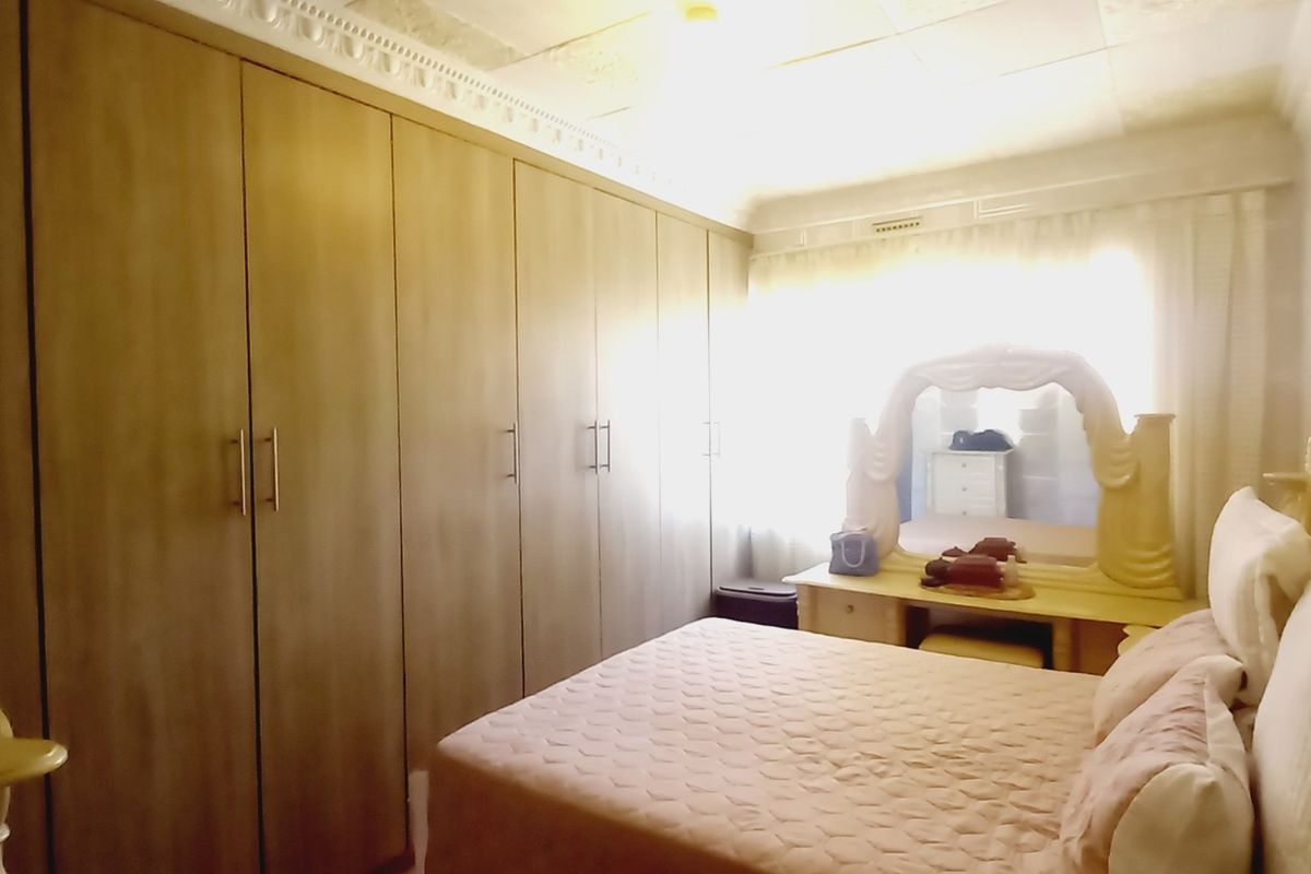 A bedroom featuring extensive built-in cupboards and decorative ceiling cornicing, offering ample storage space.