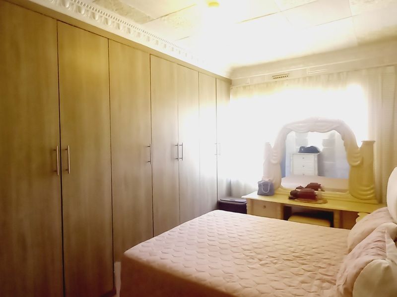 A bedroom featuring extensive built-in cupboards and decorative ceiling cornicing, offering ample storage space.