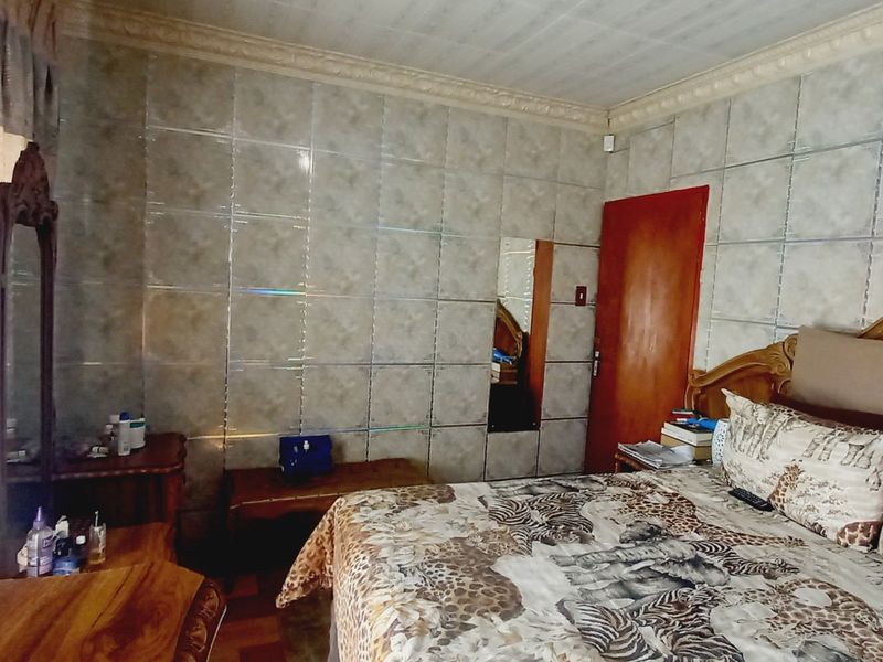 A bedroom featuring tiled wall finishes and decorative ceiling cornicing, requiring cosmetic updates to modernize the space.