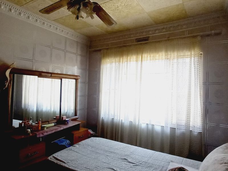A bedroom featuring decorative ceiling tiles, crown molding, and wall tiling, offering a dated aesthetic that could be modernized with updated finishes.