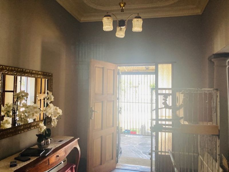Entrance foyer featuring a classic timber door, security gate, and decorative ceiling detailing, providing a welcoming transition into the home.
