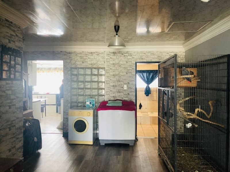 A laundry area featuring vinyl flooring, a glass block feature wall, and a coved ceiling, with direct access to adjacent rooms.
