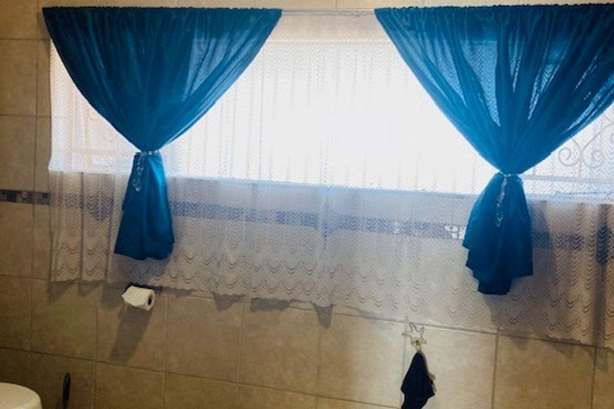 A functional bathroom featuring a built-in bathtub, ceramic wall and floor tiling, and a standard toilet.