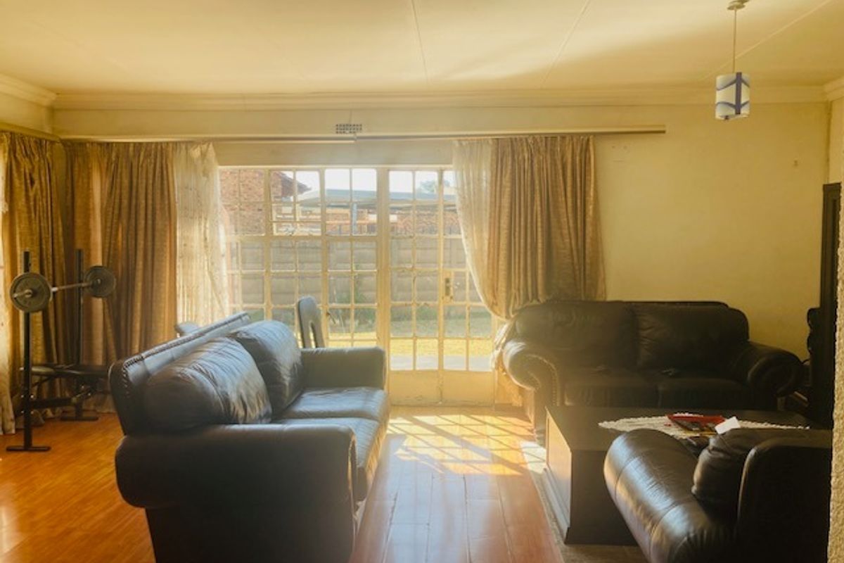 A spacious living room featuring laminate flooring and large glass french doors that provide natural light and access to the rear garden area.