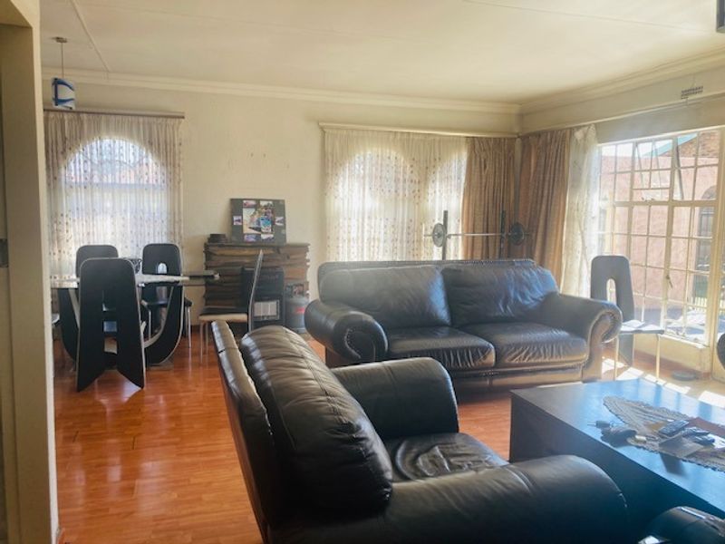 Spacious open-plan living and dining area featuring laminate flooring, arched windows, and coved cornicing, offering a versatile layout for family living.