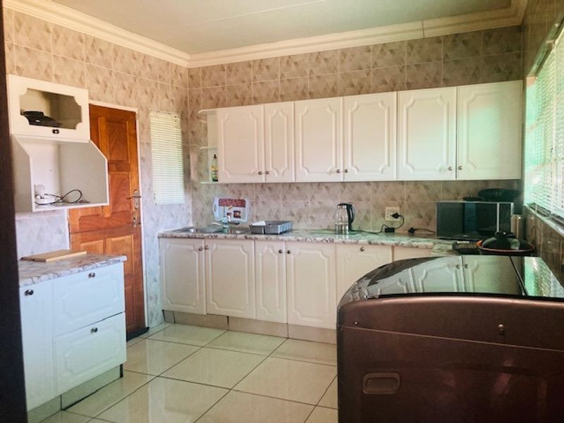 A functional kitchen featuring white cabinetry, tiled backsplash, and tiled flooring, providing ample storage and workspace for daily meal preparation.