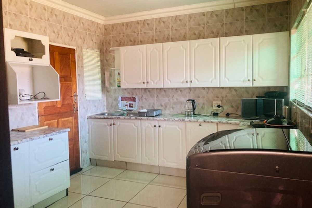 A functional kitchen featuring white cabinetry, tiled backsplash, and tiled flooring, providing ample storage and workspace for daily meal preparation.
