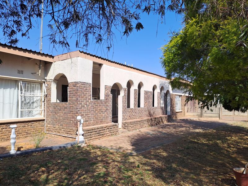 Rear exterior view of the house featuring a brick facade with arched architectural details and a paved patio area.