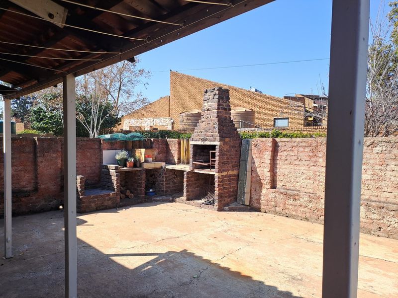 Outdoor patio area featuring a traditional brick built-in braai and perimeter wall, providing a functional space for outdoor entertaining.