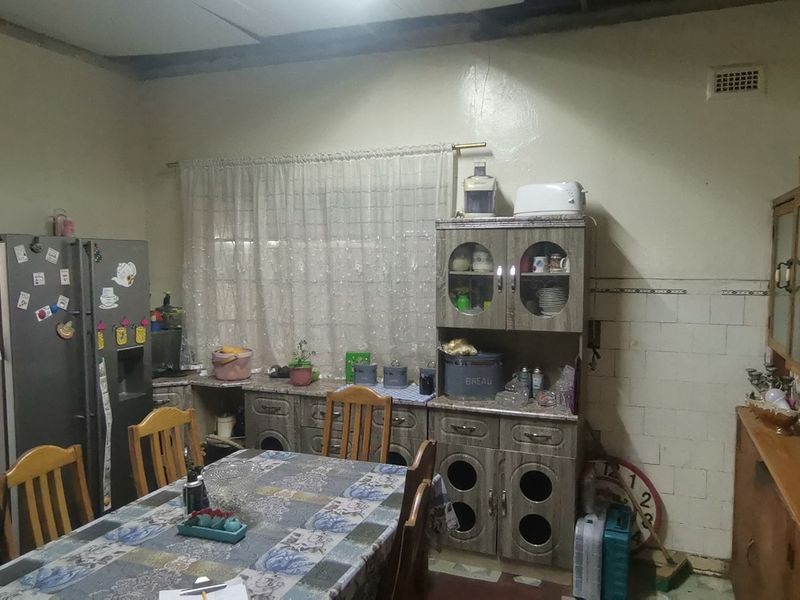 A dated kitchen featuring traditional built-in cabinetry and tiled splashbacks, offering significant potential for modernization and renovation.