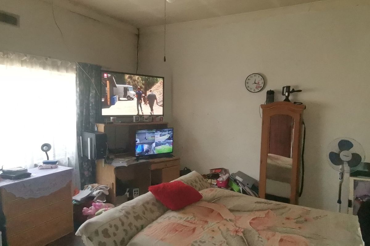 A bedroom space featuring visible structural cracking on the walls and ceiling, requiring maintenance and cosmetic updates.