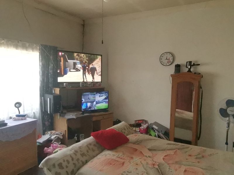 A bedroom space featuring visible structural cracking on the walls and ceiling, requiring maintenance and cosmetic updates.
