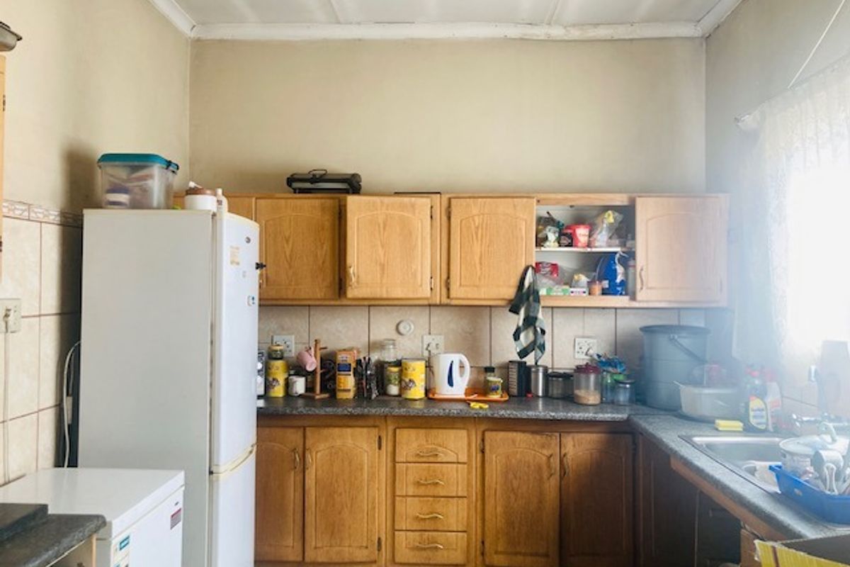 A functional kitchen featuring traditional wood-look cabinetry, laminate countertops, and a tiled backsplash, offering a dated aesthetic ready for modernization.