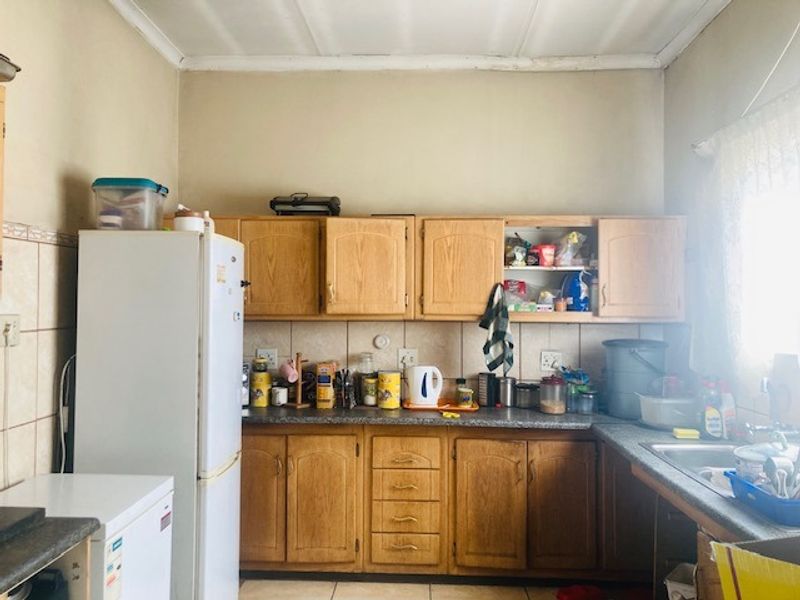 A functional kitchen featuring traditional wood-look cabinetry, laminate countertops, and a tiled backsplash, offering a dated aesthetic ready for modernization.