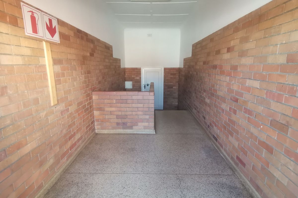 A clean, functional apartment hallway featuring exposed brick walls and durable terrazzo flooring, providing a simple and well-maintained communal access area.