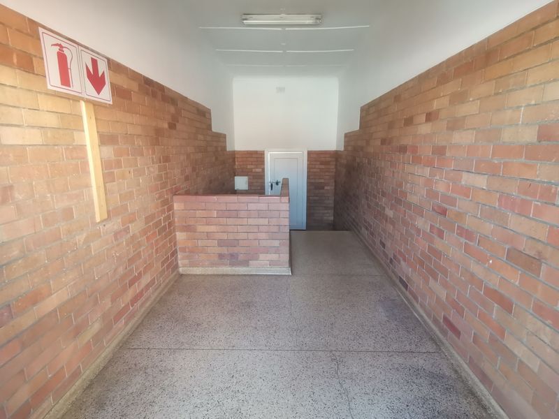 A clean, functional apartment hallway featuring exposed brick walls and durable terrazzo flooring, providing a simple and well-maintained communal access area.