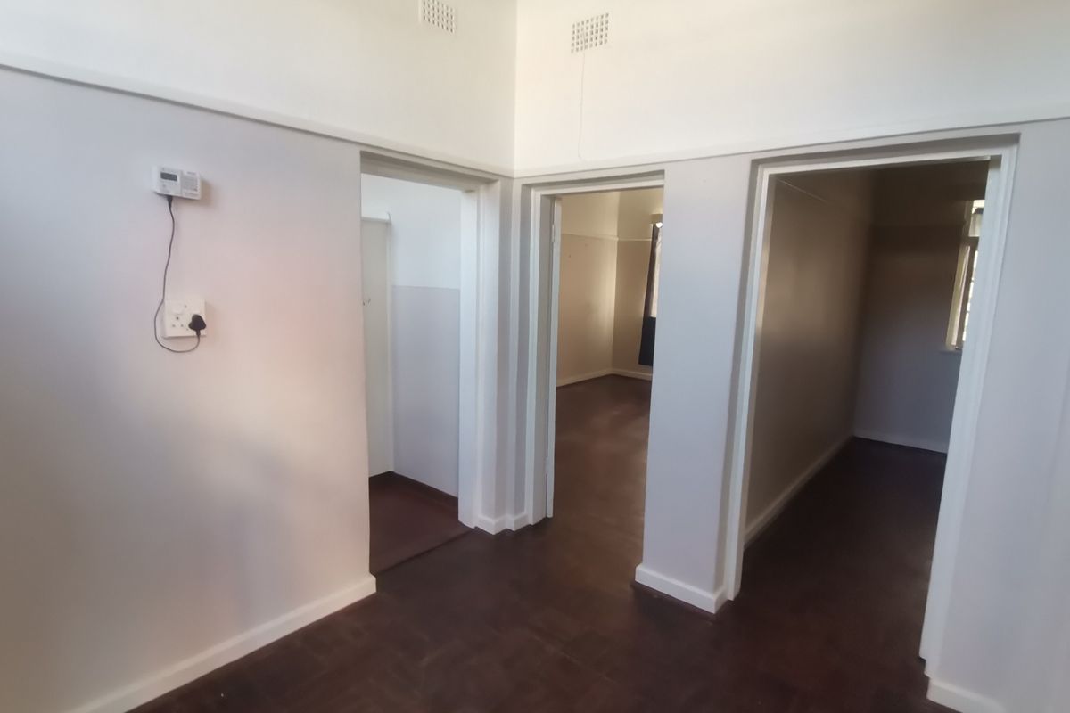 A vacant hallway featuring parquet flooring and multiple doorways leading to adjacent rooms, finished with neutral wall paint.