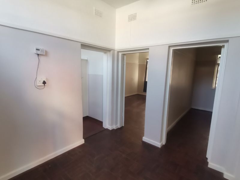 A vacant hallway featuring parquet flooring and multiple doorways leading to adjacent rooms, finished with neutral wall paint.