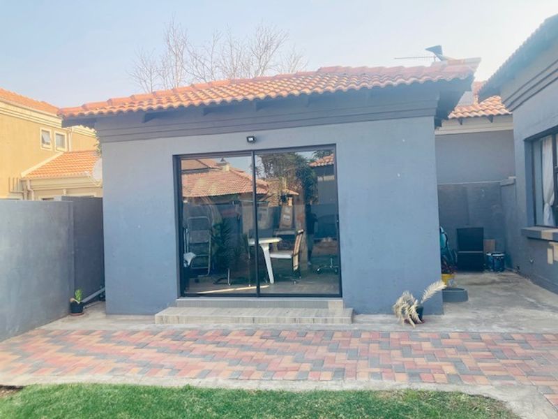 Rear view of the property featuring a paved patio area and a sliding glass door entrance.