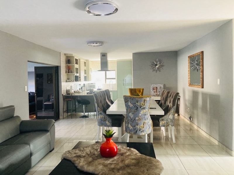 Spacious open-plan living and dining area featuring tiled flooring, a modern kitchen island with an extractor fan, and neutral wall finishes.