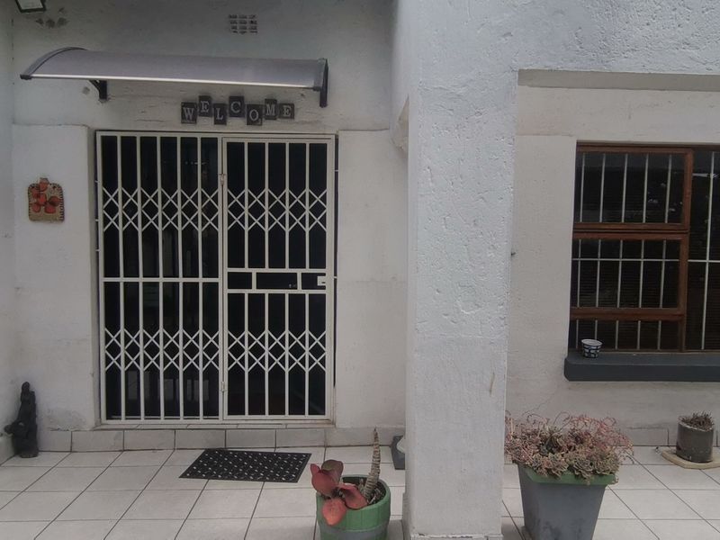 Entrance area featuring tiled flooring, a security gate, and a protective awning over the doorway.