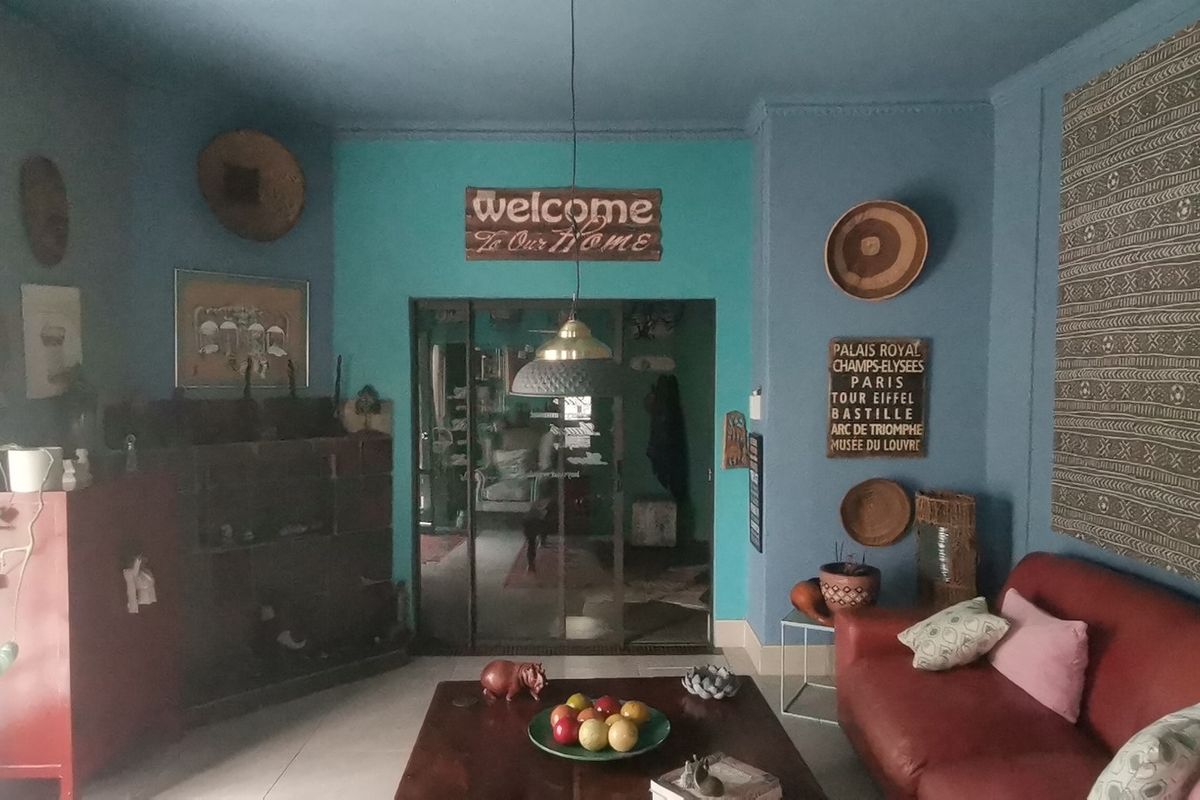 A living room featuring blue painted walls, tiled flooring, and a sliding glass door leading to an adjacent space.