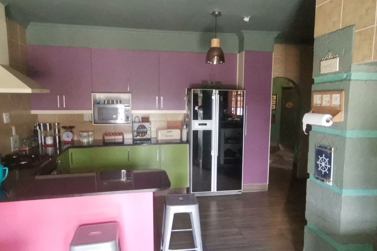 A kitchen featuring built-in cabinetry, a breakfast counter, and integrated appliances, currently finished with a dated color palette.