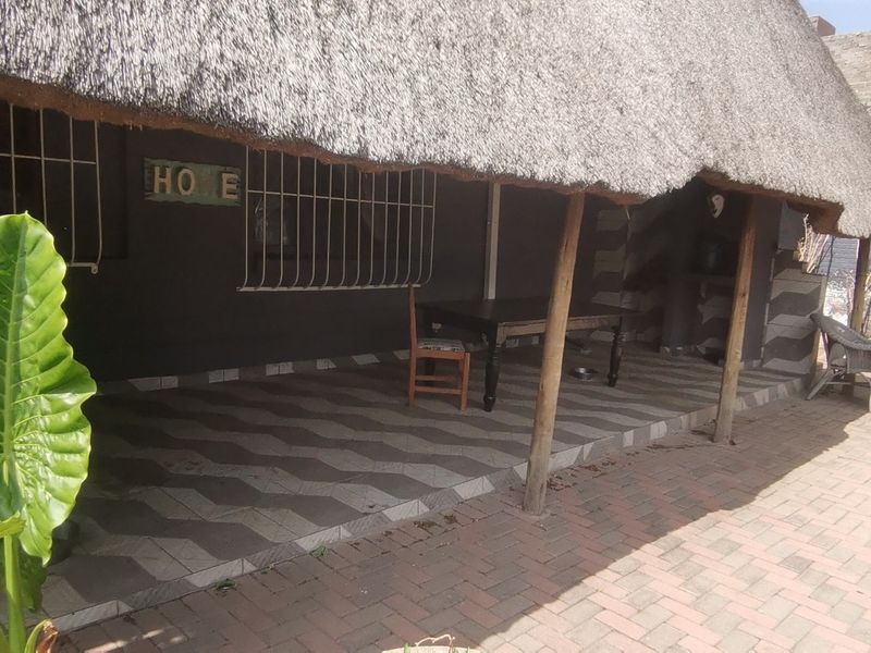 Covered patio area featuring a traditional thatched roof, tiled flooring, and security bars, providing a functional outdoor entertainment space.
