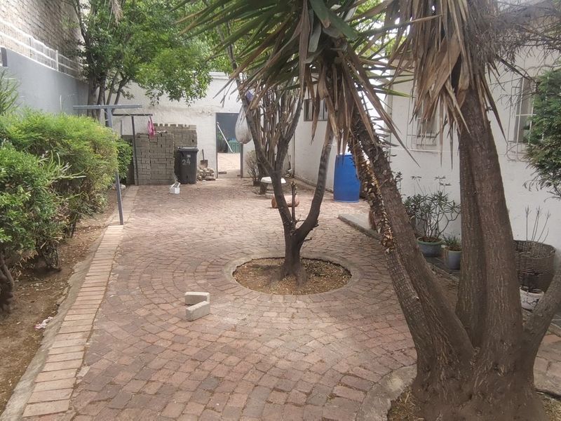 A rear courtyard area featuring brick paving, boundary walls, and established trees, offering potential for landscaping and outdoor improvement.