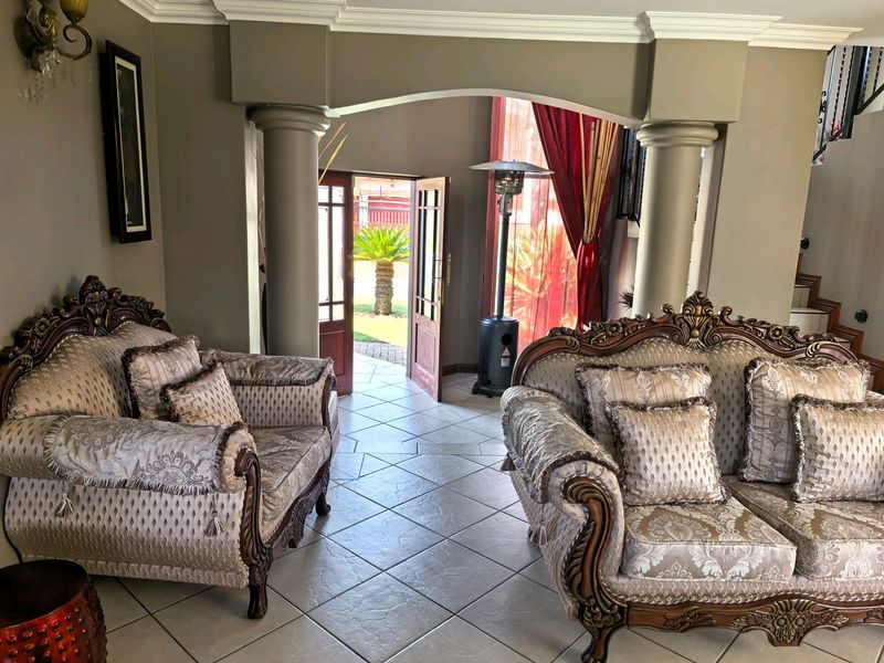 A spacious living area featuring elegant architectural columns, an arched entryway, and tiled flooring, providing a seamless transition to the outdoor garden space.