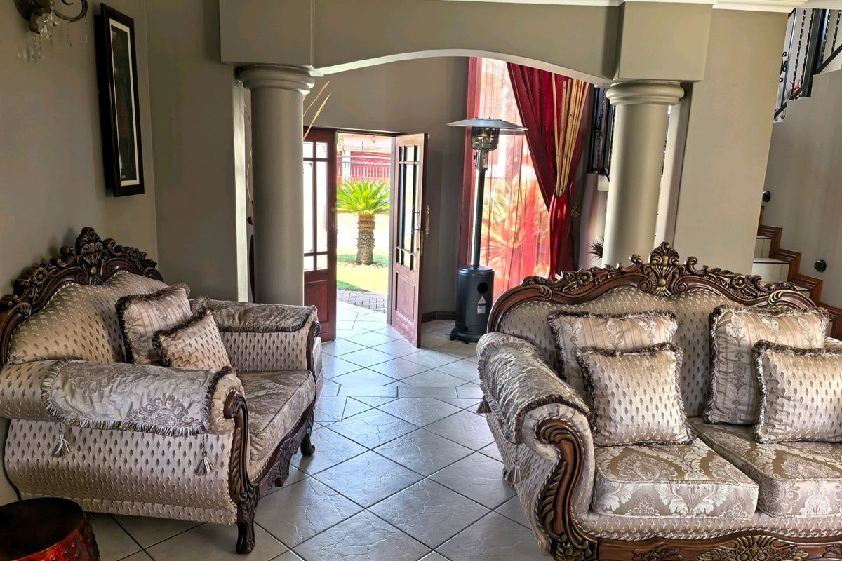 A spacious living area featuring elegant architectural columns, an arched entryway, and tiled flooring, providing a seamless transition to the outdoor garden space.