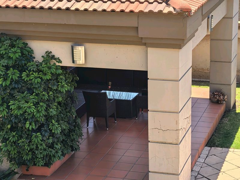 A covered patio area featuring tiled flooring and masonry columns, providing a sheltered outdoor space for relaxation and entertainment.