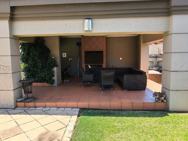 Covered patio area featuring a built-in braai, tiled flooring, and direct access to the garden.