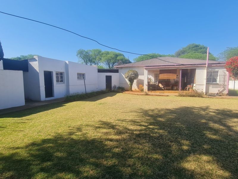 A spacious rear garden featuring a well-maintained lawn, a covered patio area, and secure boundary walls.