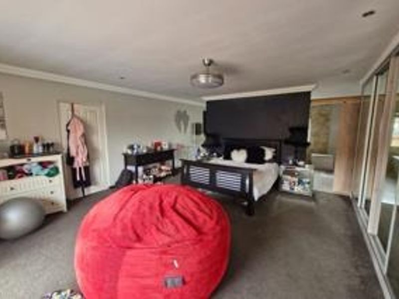 Spacious bedroom featuring recessed downlighting, coving, and large sliding door wardrobes, offering ample storage and a neutral base for interior design.