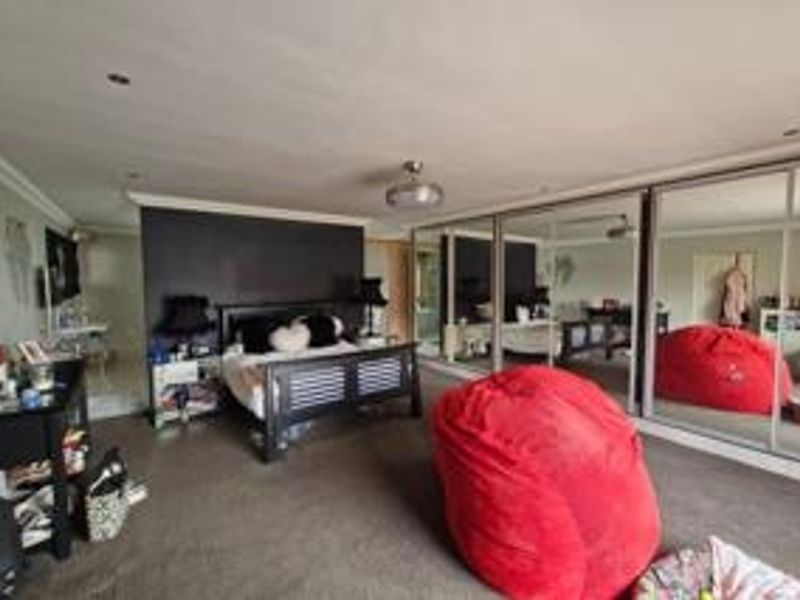 Spacious bedroom featuring large built-in mirrored wardrobes, recessed ceiling lighting, and neutral carpeting.