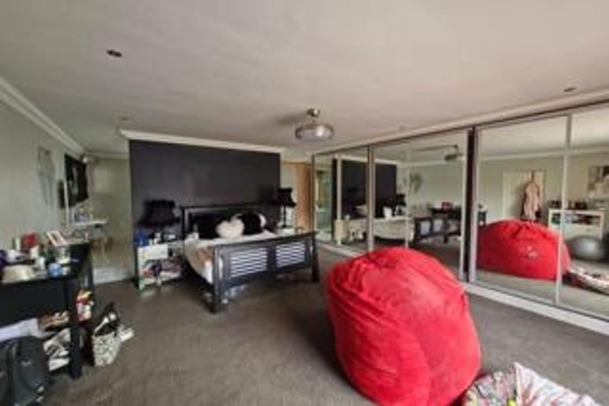 Spacious bedroom featuring large built-in mirrored wardrobes, recessed ceiling lighting, and neutral carpeting.