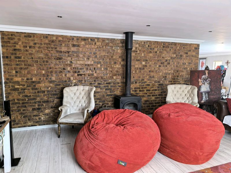 Living room featuring a prominent exposed brick wall and a central freestanding wood-burning fireplace, complemented by light-toned laminate flooring and recessed lighting.