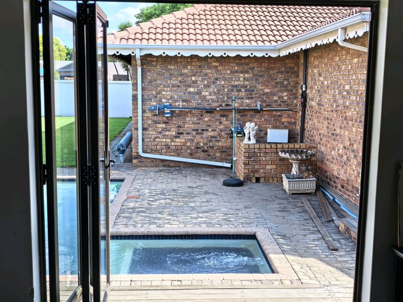 Outdoor pool area featuring brick paving, a swimming pool, and exposed brick walling, viewed from an interior doorway.