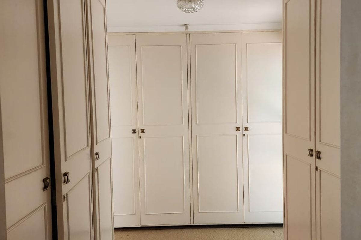 A bedroom interior featuring extensive built-in cabinetry and storage cupboards, providing ample space for organization.