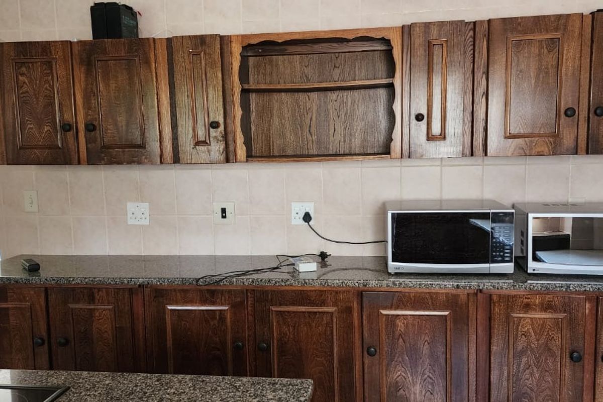 A kitchen featuring traditional dark wood cabinetry, granite countertops, and a tiled backsplash, providing a functional workspace with integrated microwave.