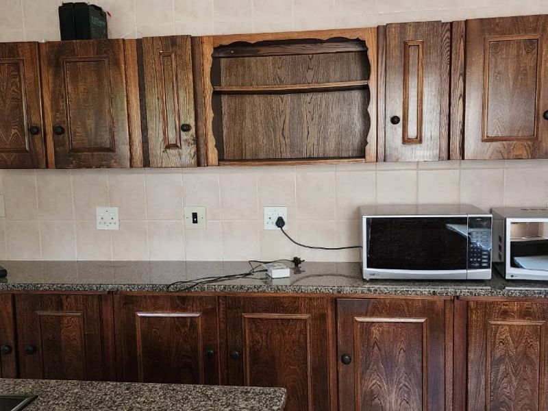 A kitchen featuring traditional dark wood cabinetry, granite countertops, and a tiled backsplash, providing a functional workspace with integrated microwave.